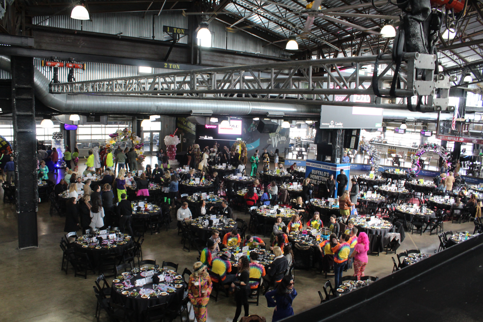 Banquet tables filling the main floor with the large screen and signage above