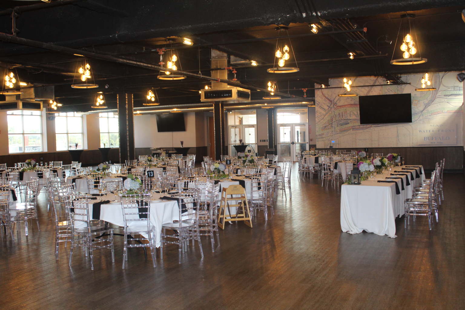 The Silos Event Center set with round tables, chiavari chairs and a head table in front of the Ganson Street murals