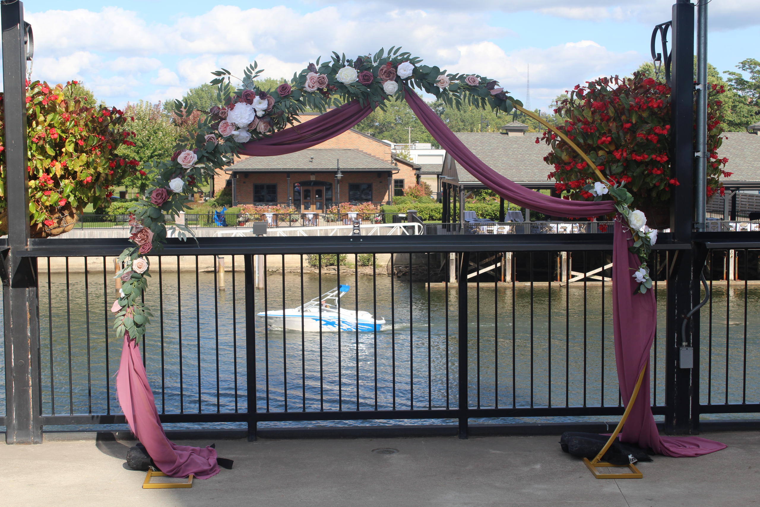 Floral and draped arch on the patio railing above the water