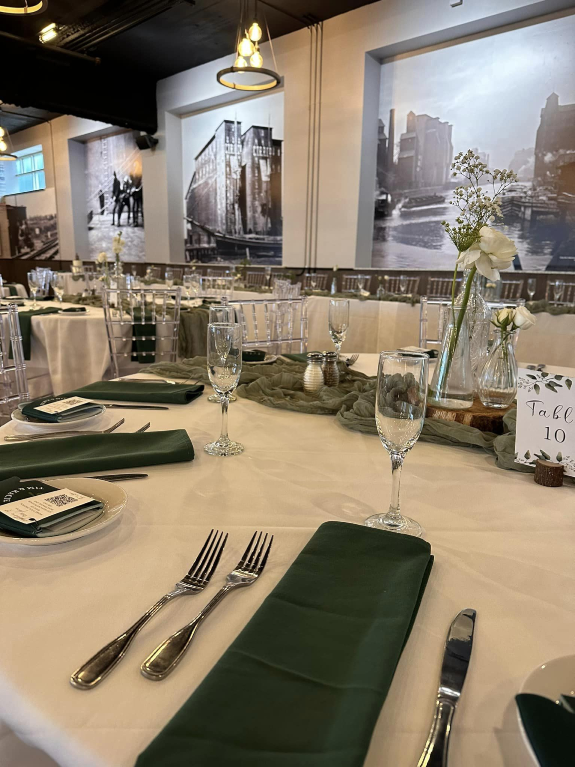 Place setting with a green napkin and polished flatware on white linen