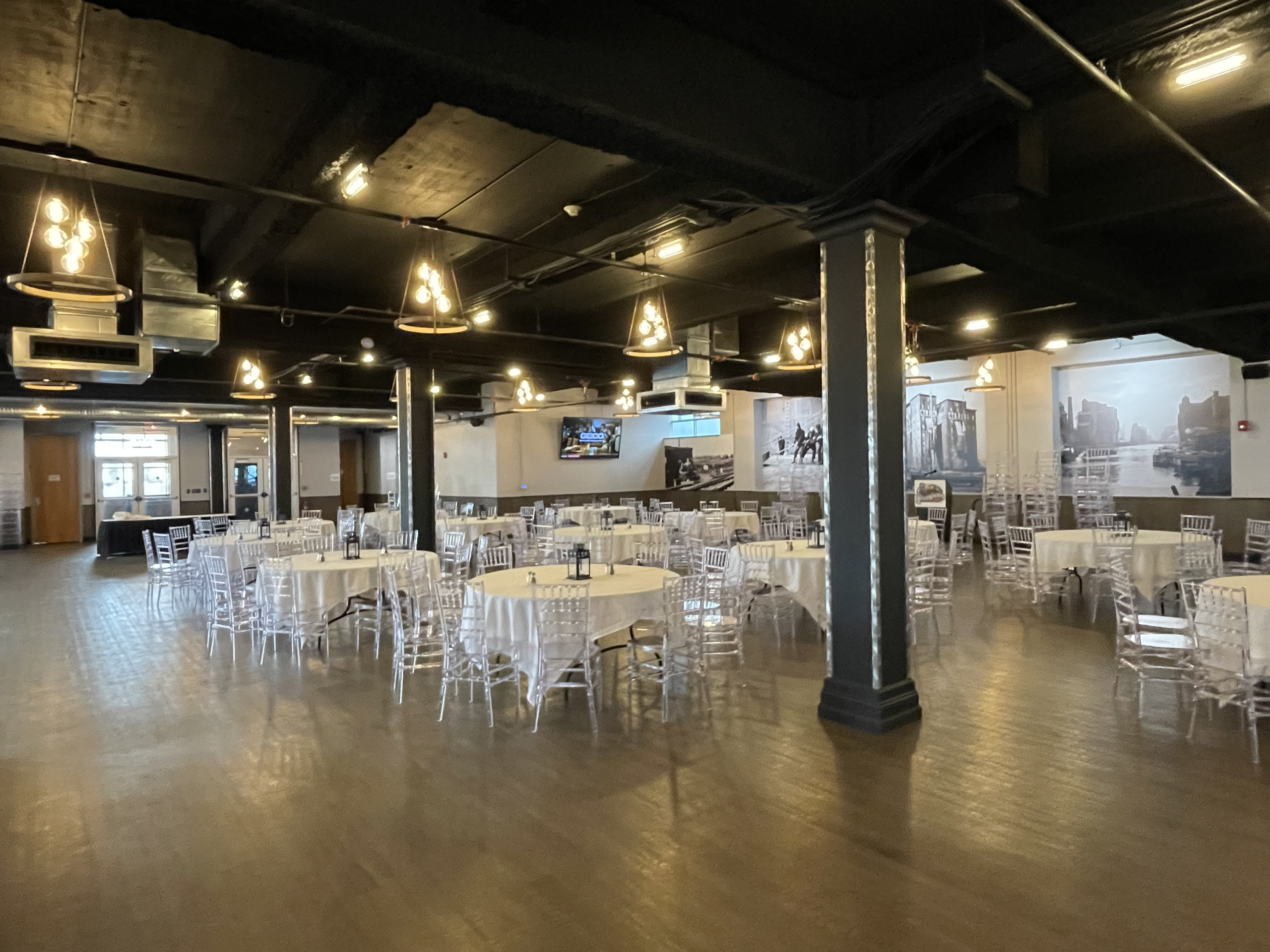 Steel beams and round banquet tables across the Silos Event Center floor