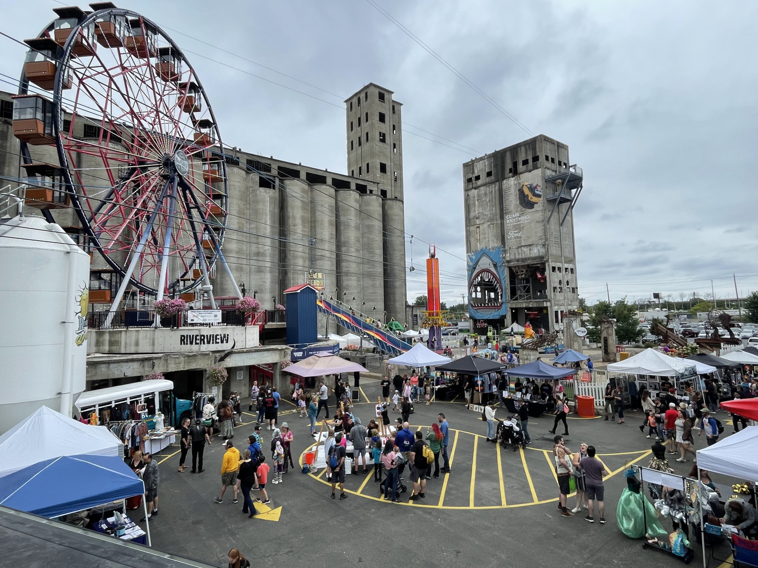 The Buffal-O Ferris Wheel and the silos above an outdoor event with vendor tents
