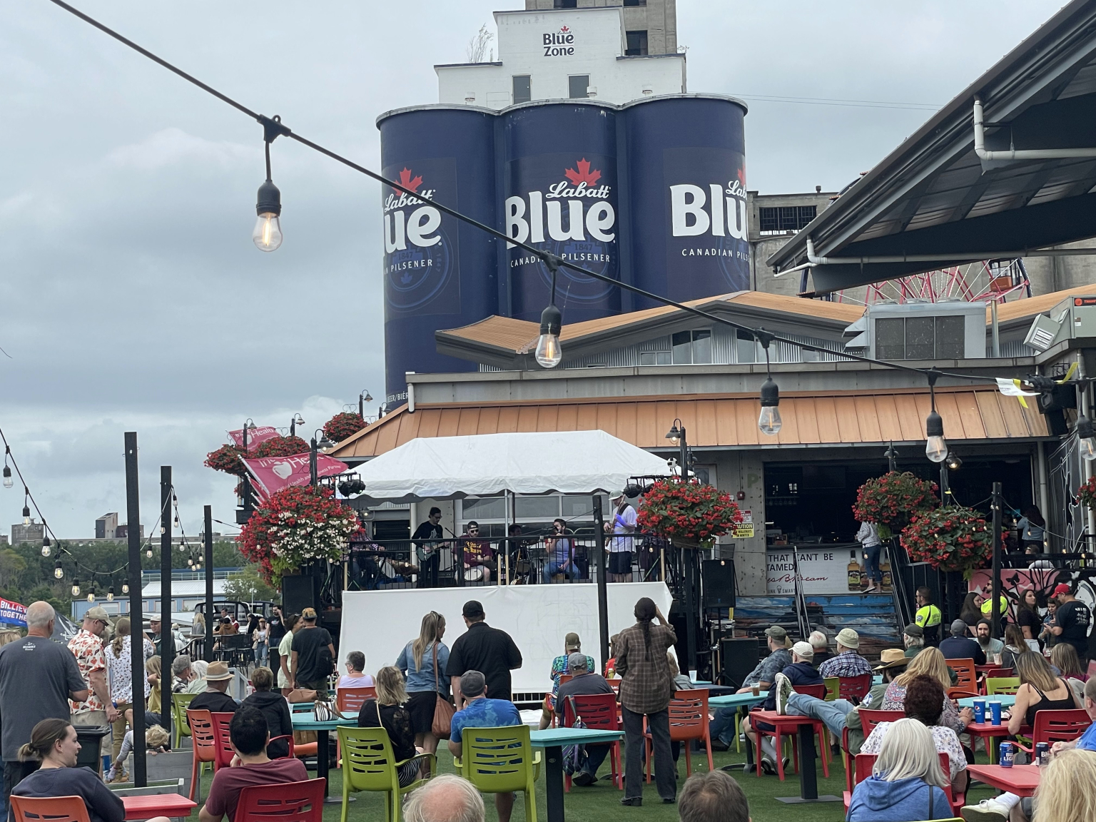 Guests seated outside under string lights beside the Labatt Blue silos