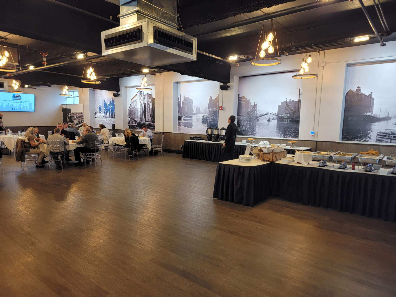 Buffet line with chafing dishes set along the side of the room while guests dine at the rounds