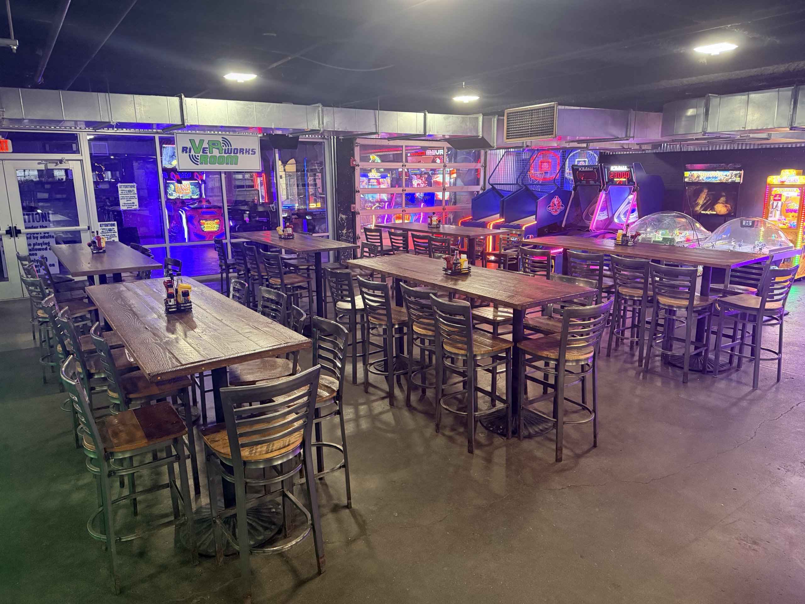 Communal tables in the Jamezone bar beside the lit arcade games
