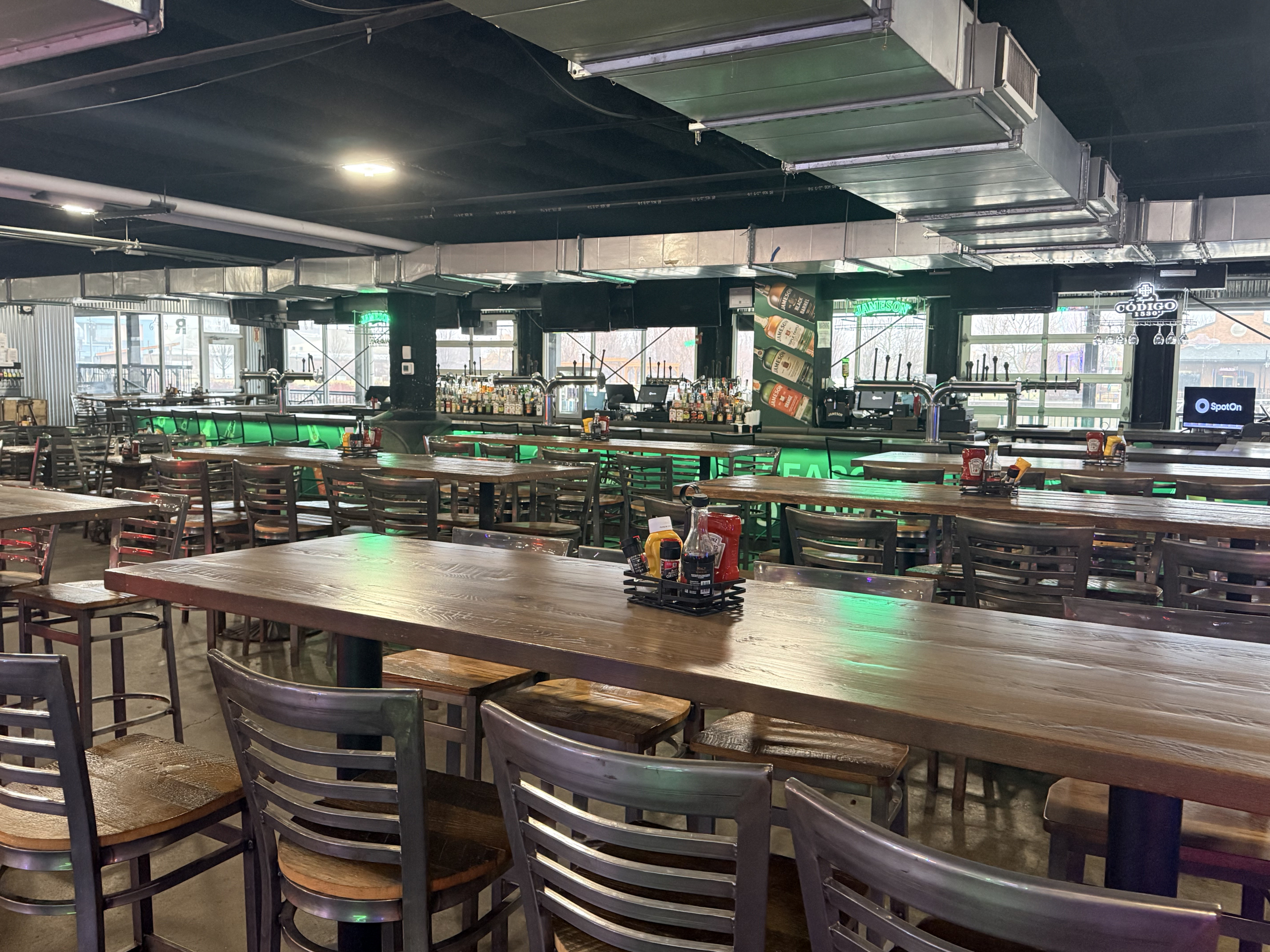 The Jamezone bar with long shared tables and green accent lighting