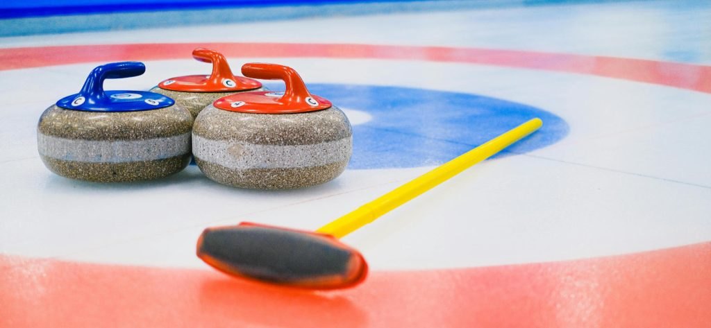 Curling stones and broom on the ice