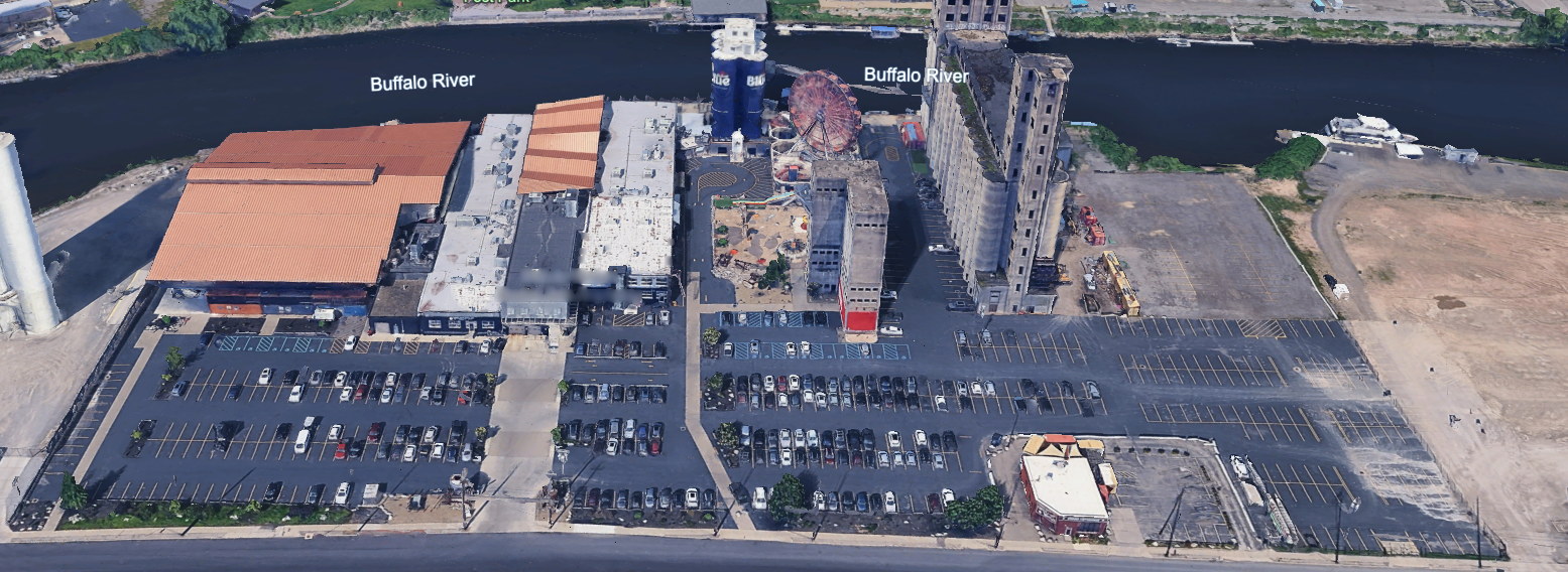 Aerial photograph of the Buffalo RiverWorks property on the Buffalo River, showing the ice rink building, the main building, the Labatt Blue silos, the ferris wheel, the grain elevator and the parking lots.
