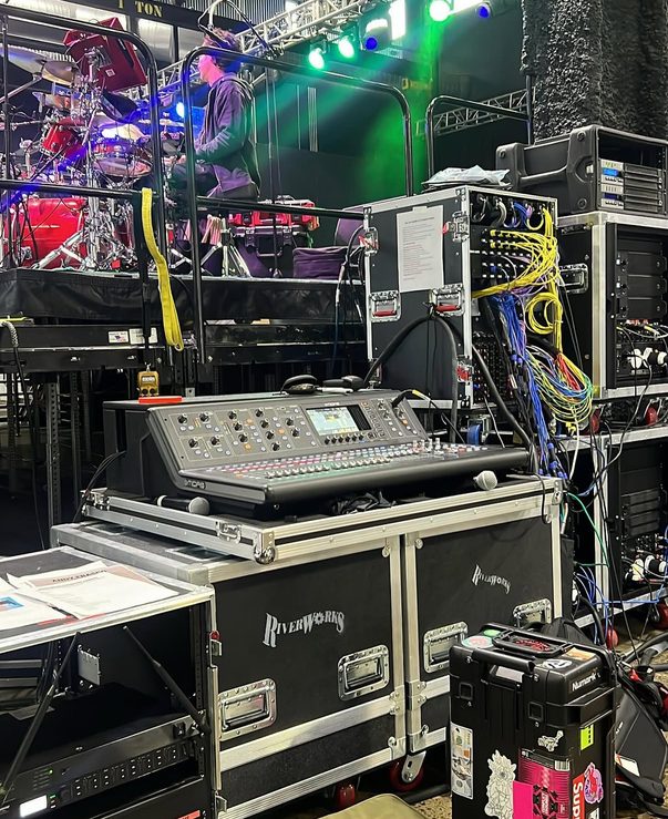 Midas M32 monitor console in a road case beside the stage.