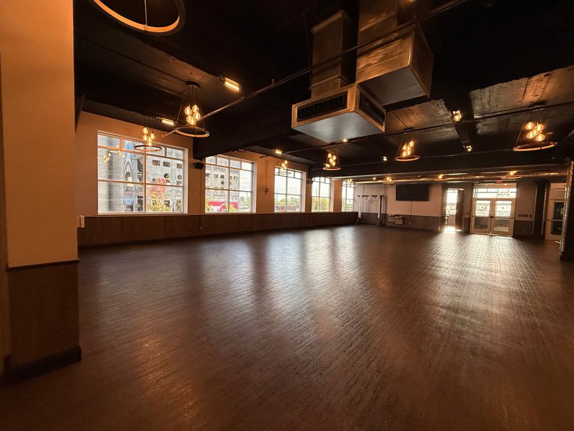 Large multi-artist backstage room with wood floor and catering area.