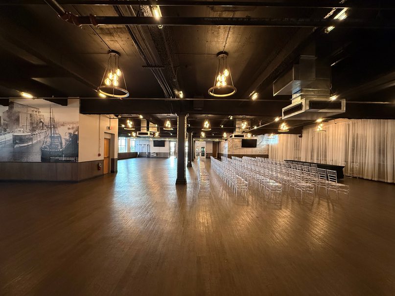 Long backstage hall with chairs set out and pendant lights.