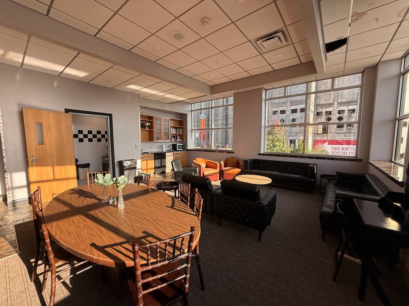 Green room with a round wood table, couches and windows.