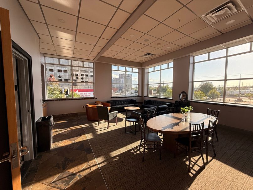 Green room seating area with a round table and large windows.