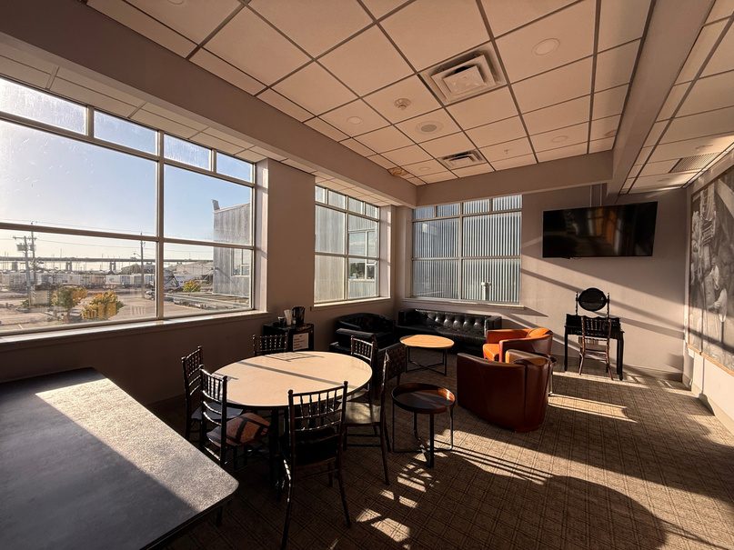 Green room with a round table, leather chairs and a wall TV.